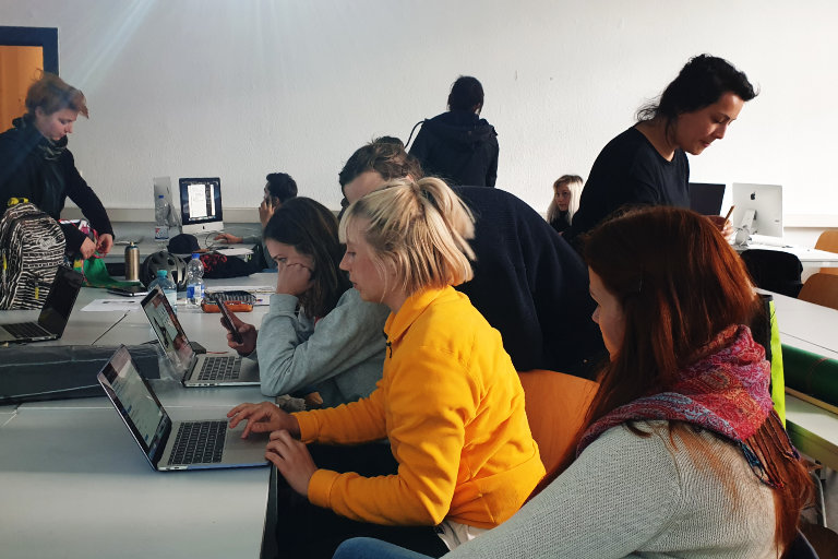 Studierende sitzen an den Tischen im Mediastudio vor ihren Computern und bearbeiten die Website. 