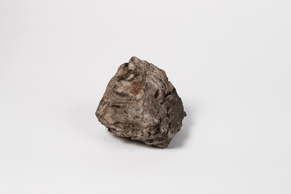 Zu sehen ist ein faustgroßer Stein in Grau und Braun.