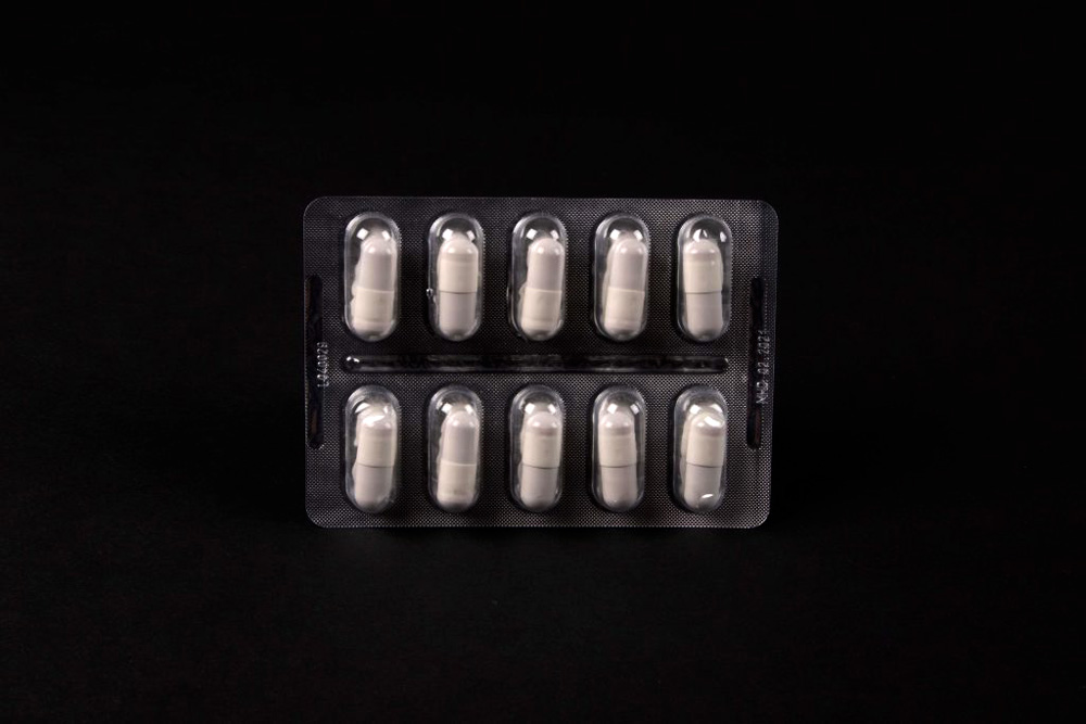 Zu sehen ist eine ungeöffnete Packung mit zehn weißen, kapselförmigen Tabletten.