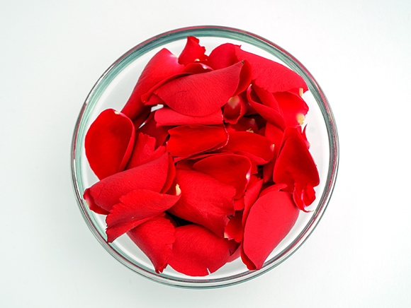 Rote Rosenblüten in einer durchsichtigen Schüssel.